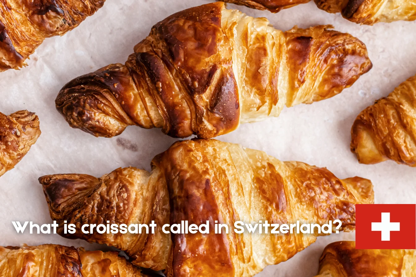 A golden-brown Swiss Gipfeli on a breakfast table with coffee, highlighting the Swiss name for croissant, Gipfeli.