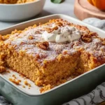 Pumpkin dump cake with whipped cream on a rustic table